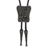 Bolo tie i rektangulär mörk metall med blommigt vintagemönster